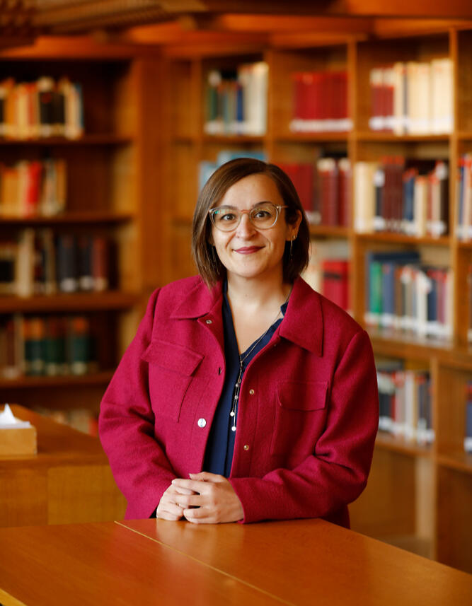Image of Özgün Ünver wearing glasses, a blue blouse, and a pink blazer.